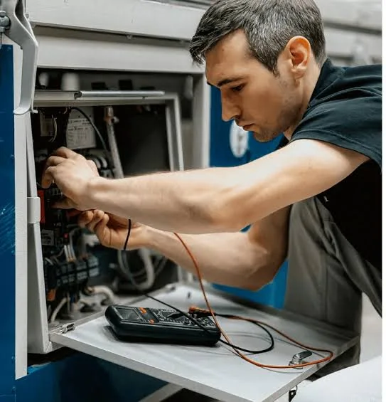 Technician using a meter while servicing an indoor furnace system