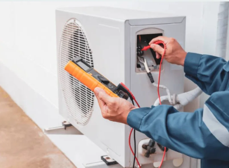 Technician checking HVAC control wiring with a digital meter